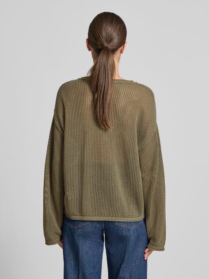 Frauenmodel trägt Loose Fit Pullover aus reiner Baumwolle Modell 'C_FARDE' von BOSS Orange in Olivgrün, grobe Strickstruktur, Ganzkörperansicht Rückansicht.