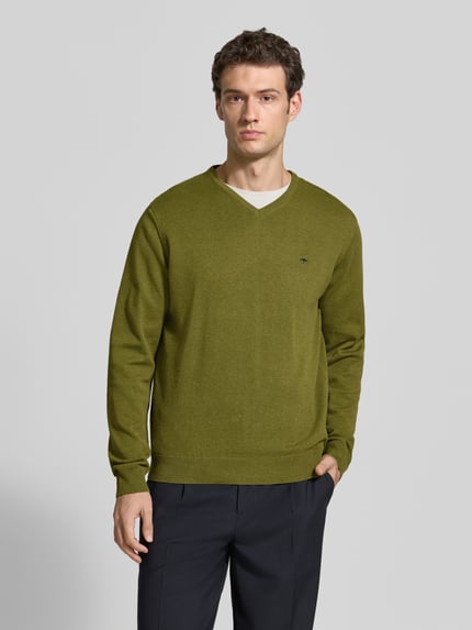 Männermodel trägt Strickpullover mit Label-Strickerei von Fynch-Hatton in Grün, V-Ausschnitt, gerader Schnitt, Ganzkörperansicht von vorne.