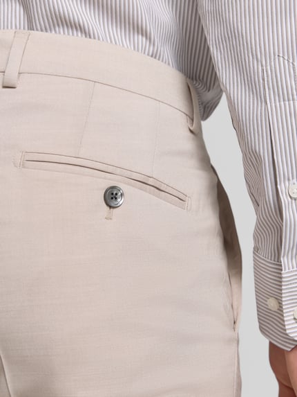 Męski model nosi Anzughose mit Gesäßtaschen Modell 'Blayr' od JOOP! Collection, beżowy, gładka tekstura, tylne kieszenie, krój prosty, mieszanka wiskozy i wełny ze stretchem, Szerokość w rozmiarze 50: 47 cm, długość nogawki: 80 cm, detal tylnej części, zbliżenie na pośladki.