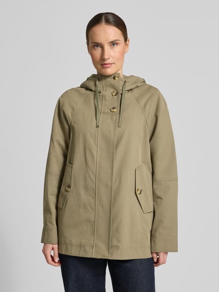 Frauenmodel trägt Jacke mit verdecktem Reißverschluss von Fuchs Schmitt aus Baumwoll-Mix, Regular-Fit, Kapuze mit Tunnelzug, Pattentaschen, Farbe Olive, glatte Textur, Rückenlänge 73 cm, Schulterbreite 37 cm, Brustweite 54 cm, Ärmellänge 66 cm, Ganzkörperansicht von vorne.