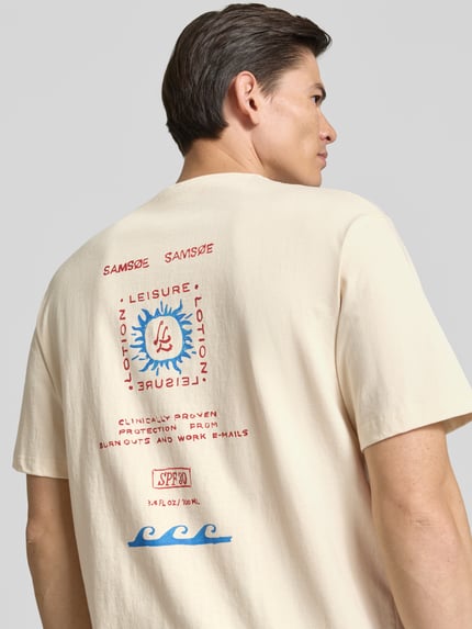 Männermodel trägt T-Shirt mit Label-Print Modell 'GERGEI' von Samsøe Samsøe in Beige, Baumwolle, Relaxed Fit, Rückenansicht, Nahaufnahme Oberkörper.