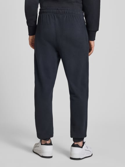 Männermodel trägt Sweatpants mit Logo-Stitching Modell 'ORVINIO' von Ellesse in Dunkelblau, Slim Fit, Rückansicht, Baumwoll-Mix.