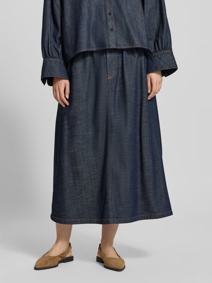 Frauenmodel trägt dunkelblauen Jeansrock aus Lyocell-Mix mit Bindegürtel Modell 'EDMEA' von Drykorn, Gerader-Schnitt, Midirock, Nahaufnahme Unterkörper. Bundweite bei Größe 27: 37 cm, Gesamtlänge bei Größe 27: 89 cm.