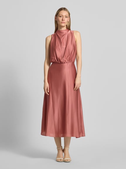 Frauenmodel trägt Cocktailkleid mit Stehkragen von Swing in Rosa, taillierte Passform, Midikleid, Ganzkörperansicht von vorne. Rückenlänge 126 cm, Brustweite 34 cm, Rückenreißverschluss, Unterkleid.