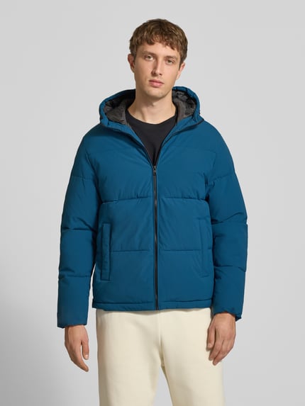 Męski model nosi kurtkę pikowaną z kapturem Model 'GALAXY' od JACK & JONES, krój regular fit, wpuszczane kieszenie, zamek błyskawiczny, niebieski kolor, tkanina matowa, długość tyłu w rozmiarze M: 70 cm, szerokość ramion w rozmiarze M: 49 cm, szerokość klatki piersiowej w rozmiarze M: 58 cm, długość rękawów w rozmiarze M: 69 cm, zdjęcie całej sylwetki z przodu