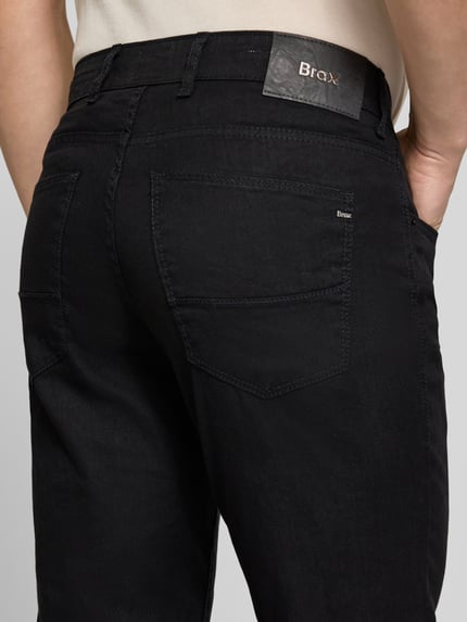 Männermodel trägt Regular Fit Stoffhose aus Baumwoll-Leinen-Mix Modell 'CADIZ' von Brax, vijfzakken, uni, label patch, knoopsluiting, detailaufnahme achterkant.