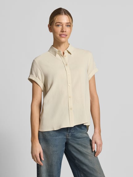 Frauenmodel trägt Bluse aus Viskose-Mix mit fixiertem Ärmelaufschlag von Samsøe Samsøe, heller Ton, glatte Textur, gerader Schnitt, Knopfleiste, Kentkragen, Leinen-Anteil, Ganzkörperansicht von vorne.