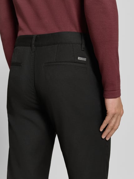 Männermodel trägt Straight Fit Hose mit Viskose-Anteil von Armani Exchange in Schwarz, feine glatte Textur, Detailaufnahme Rückansicht, Herren Hose von Armani, Elastischer Material-Mix mit Viskose-Anteil, Eingriff- und Gesäßtaschen, Knopf- und Reißverschluss, Bundweite bei Größe 32/32: 44 cm, Innenbeinlänge bei Größe 32/32: 84 cm.