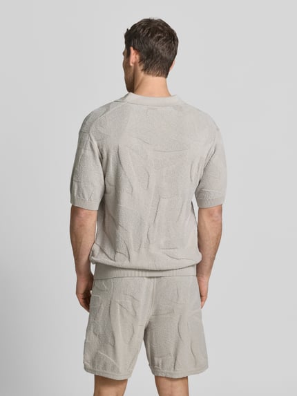 Männermodel trägt Relaxed Fit Poloshirt aus reiner Baumwolle Modell 'ASURFO' von BOSS Orange in Optik: Unifarben, Struktur, Ganzkörperansicht Rückansicht.