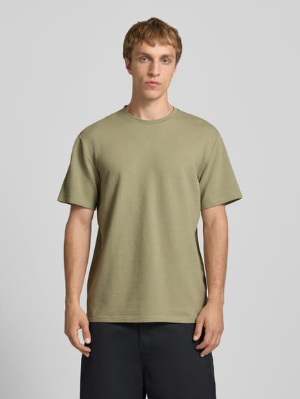 Männermodel trägt Regular Fit T-Shirt aus Baumwoll-Mix Modell 'KIAN' von Only & Sons, Optik: Unifarben, Piqué-Struktur, Ganzkörperansicht von vorne.