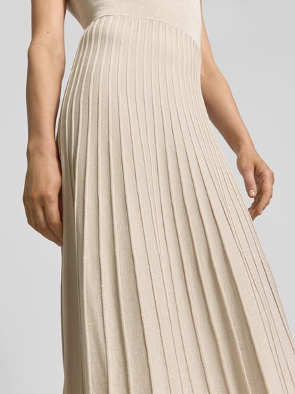 Vrouwenmodel draagt midi-jurk uit viscosemix met plissévouwen van comma, getailleerd model, ronde hals, detailopname onderlichaam.