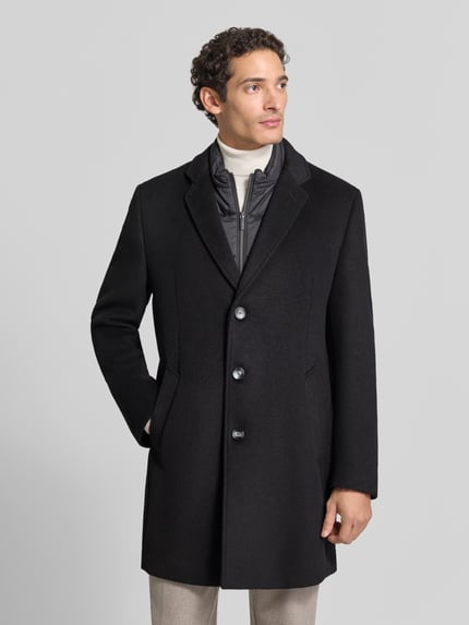 Męski model nosi Regular Fit Mantel im 2-in-1-Look od bugatti, Mieszanka wełny, Kołnierz z połami, Listwa guzikowa, Wpuszczane kieszenie, Długość tyłu w rozmiarze 50: 93 cm, Szerokość ramion w rozmiarze 50: 45 cm, Szerokość w rozmiarze 50: 55 cm, Długość rękawów: 68 cm, efekt 2 w 1, czarny, matowa tekstura, Ganzkörperansicht z przodu.