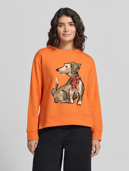 Frauenmodel trägt orangefarbenes Sweatshirt mit Hundeprint von MILANO ITALY, mehrfarbiger Motiv-Print, Jersey, Nahaufnahme Oberkörper.