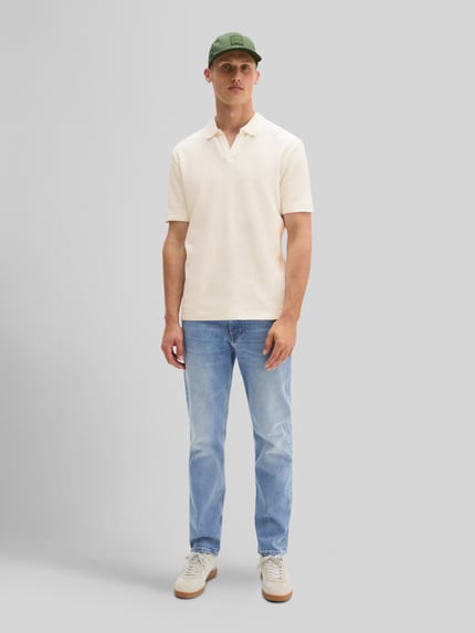 Männermodel trägt Regular Fit T-Shirt aus reiner Baumwolle von Marc O'Polo in Creme, kombiniert mit blauer Jeans, Ganzkörperansicht von vorne. Herren T-Shirt von Marc O'Polo