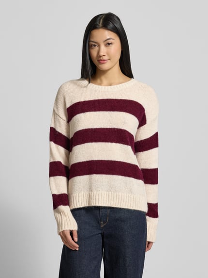 Frauenmodel trägt Strickpullover mit Rundhalsausschnitt von Milano Italy, gestreift in Creme und Dunkelrot, Material-Mix mit Alpaka-Anteil, Regular Fit, Rundhalsausschnitt, überschnittene Schultern, Ganzkörperansicht von vorne.