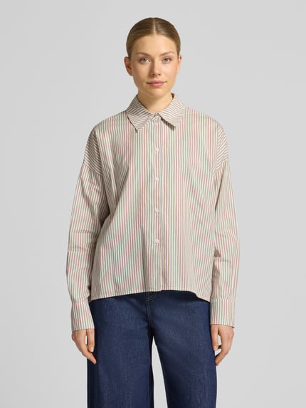 Frauenmodel trägt Relaxed Fit Bluse mit überschnittenen Schultern Modell 'CLOELIA' von Drykorn, feine Streifen, reine Baumwolle, Hemdblusenkragen, Ganzkörperansicht von vorne.