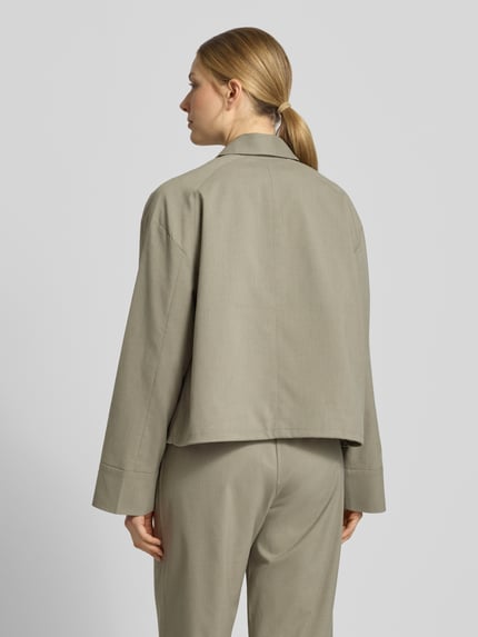 Frauenmodel trägt Jacke mit Eingrifftaschen Modell 'KELLY' von Samsøe Samsøe in hellem Beige, glatte Textur, Material-Mix, Ganzkörperansicht Rückansicht.