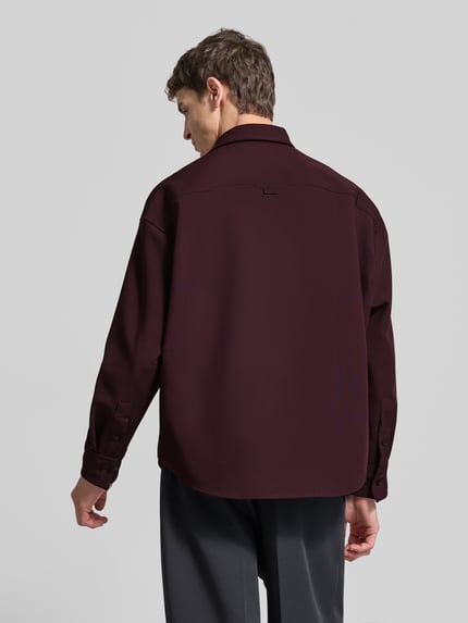Männermodel trägt Oversized Hemdjacke mit Kentkragen Modell 'STUDIO' von SEIDENSTICKER, Regular Fit, elastisches Material, langärmelig, Rückenansicht, Freizeithemd, tiefroter Farbton, strukturierte Oberfläche, Ganzkörperansicht Rückansicht.