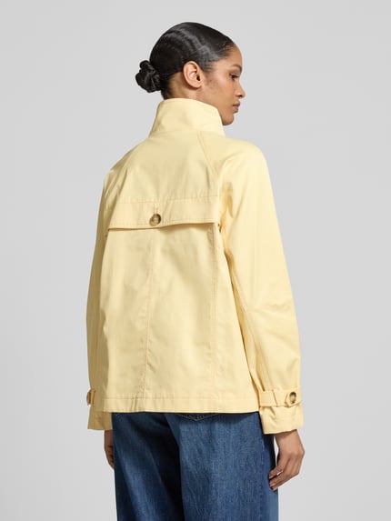 Frauenmodel trägt Jacke mit Stehkragen und Ärmelriegeln von Fuchs Schmitt im Baumwoll-Mix, Regular-Fit, Rückansicht Ganzkörperansicht. Eingrifftaschen, Knopfleiste, cremefarbener Stoff mit matter, glatter Oberfläche, Rückenlänge 67 cm, Schulterbreite 42 cm, Brustweite 52 cm, Ärmellänge 44 cm bei Größe 36.