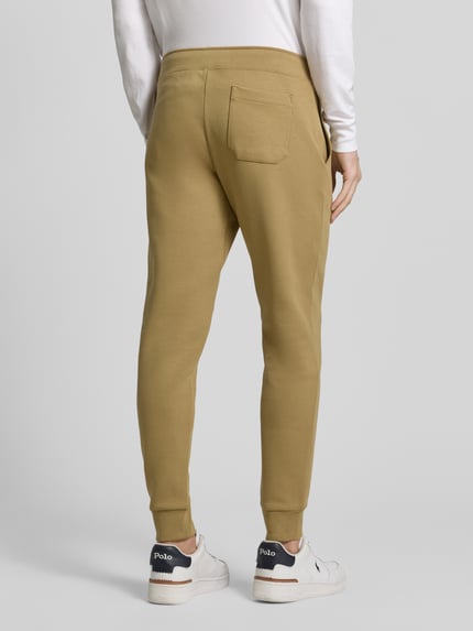 Mannelijk model draagt Tapered Sweatshorts aus Baumwoll-Mix van Polo Ralph Lauren in effen kleur met gestikt logo, achterzak, tapered pasvorm, sweat van katoenmix. Ganzkörperansicht Rückansicht.