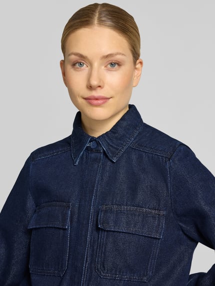 Frauenmodel trägt Jeansbluse mit Brusttaschen und Kentkragen von Stefanel in dunklem Blau, Baumwoll-Mix, Nahaufnahme Oberkörper.