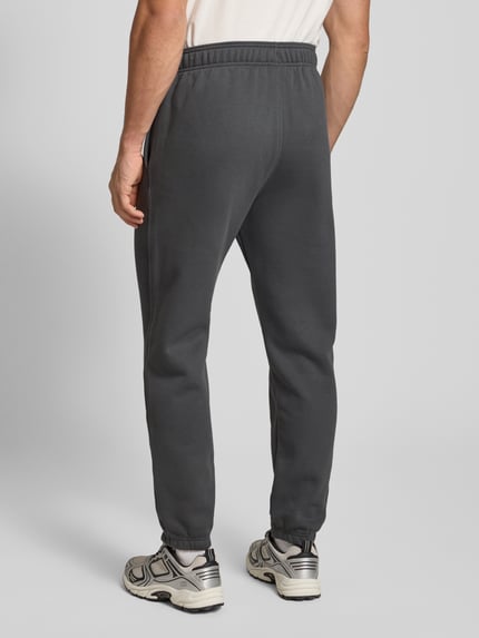 Mężczyzna nosi Sweatpants mit elastischem Bund od CHAMPION, bawełniana mieszanka, luźny krój, elastyczny pas, widok z tyłu, całe ciało.