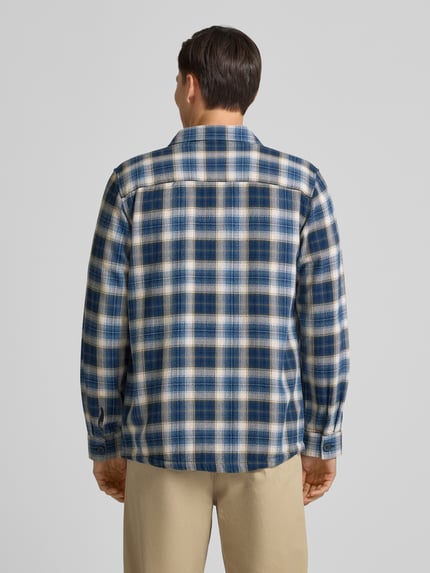 Männermodel trägt Relaxed Fit Freizeithemd mit Brusttaschen von Fynch-Hatton, kariertes Muster in Blau-Beige, reine Baumwolle, Ganzkörperansicht Rückansicht.