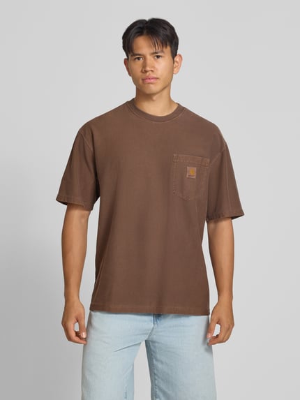 Männermodel trägt Regular Fit T-Shirt aus reiner Baumwolle Modell 'Loose Pocket' von Carhartt Work In Progress in Braun, Brusttasche, Ganzkörperansicht von vorne, Herren T-Shirt, Rückenlänge bei Größe M: 76 cm.