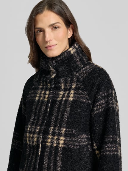 Frauenmodel trägt Kurzmantel mit Stehkragen Modell 'SC-GISA 1' von SOYACONCEPT, schwarz-beiges Karomuster, Bouclé-Struktur, Nahaufnahme Oberkörper.