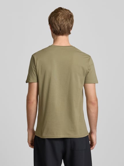 Männermodel trägt T-Shirt mit Logo und Rundhalsausschnitt von Alpha Industries, olivgrün, reine Baumwolle, Regular Fit, Ganzkörperansicht Rückansicht.
