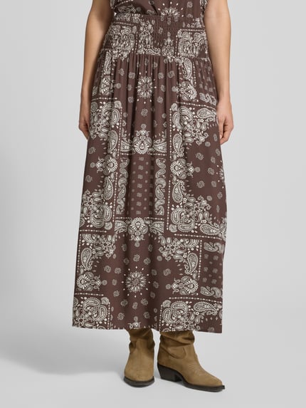 Vrouwenmodel draagt donkerbruine dames maxi rok met witte paisley patronen, Ausgestellter Maxi-Rock aus reiner Viskose Modell 'SAKI AMBEL' van Only, ganzlichaamsaanzicht van voren.