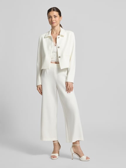 Frauenmodel trägt weiße Straight Fit Stoffhose mit Viskose-Anteil Modell 'Leonie' von GUIDO MARIA KRETSCHMER WOMAN, Ziernähte, weites Bein, Elastischer-Material-Mix, Ganzkörperansicht von vorne.