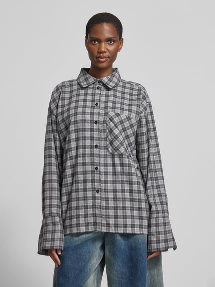Frauenmodel trägt Oversized Hemdbluse aus reiner Baumwolle von black palms in Grau mit Karomuster, Brusttasche und Knopfleiste, Ganzkörperansicht von vorne. Rückenlänge bei Größe S: 70 cm, Hemdblusenkragen.