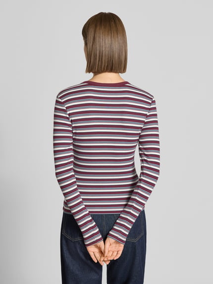 Frauenmodel trägt Regular Fit Langarmshirt aus Baumwoll-Mix Modell 'VAL' von ONLY mit Streifen in Lila, Weiß und Rot, Damen Langarmshirt, Ganzkörperansicht Rückansicht.