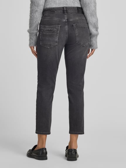 Frauenmodel trägt Mid Waist Straight Fit Jeans mit Knopfleiste von Marc O'Polo in Medium Wash Denim, Used Look, 5-Pocket-Design, Ganzkörperansicht Rückansicht.