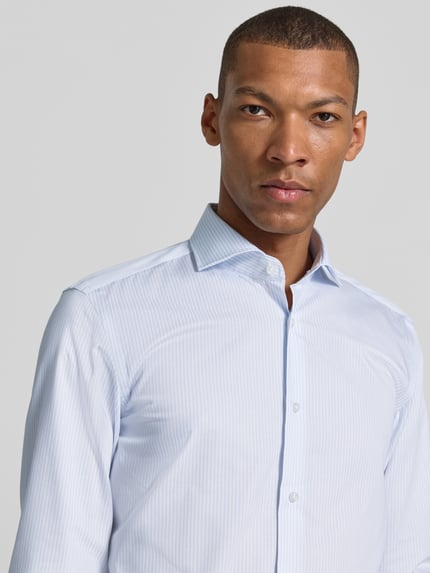 Männermodel trägt hellblau-weiß gestreiftes Slim-Fit Businesshemd aus reiner Baumwolle Modell 'H-HANK-SP-B1' von BOSS, Nahaufnahme Oberkörper, Herren Businesshemd.