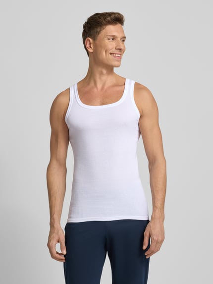 Męski model nosi Tanktop in Ripp-Optik od Götzburg, biały, slim fit, bawełna, dekolt okrągły, faktura prążkowana, widok z przodu całej sylwetki.