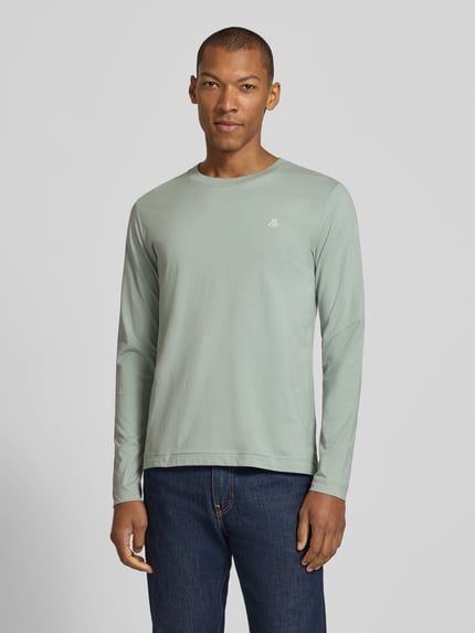 Männermodel trägt Shaped Fit Langarmshirt aus reiner Baumwolle von Marc O'Polo in Hellgrün, kombiniert mit blauer Jeans, Ganzkörperansicht von vorne, Herren Langarmshirt von Marc O'Polo