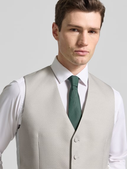 Männermodel draagt Regular Fit Weste mit v-hals van Wilvorst in lichtgrijs materiaalmix met katoen, paspelzakken, knoopsluiting. Nahaufnahme Oberkörper.