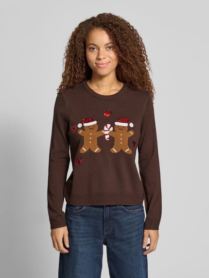 Frauenmodel trägt Rollkragenpullover mit weihnachtlichem Motiv-Print von ONLY in mehrfarbiger Strickoptik mit Pailletten und Glitzer, Ganzkörperansicht von vorne.
