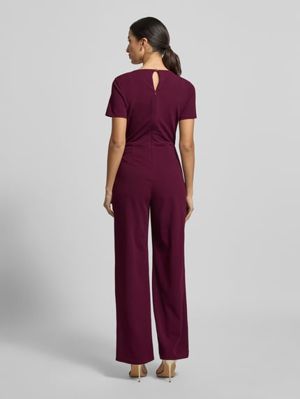 Frauenmodel trägt Regular Fit Jumpsuit mit Cut-Out von Lipsy in dunklem Bordeauxrot, elastischer Material-Mix, taillierte Passform, Ganzkörperansicht Rückansicht.