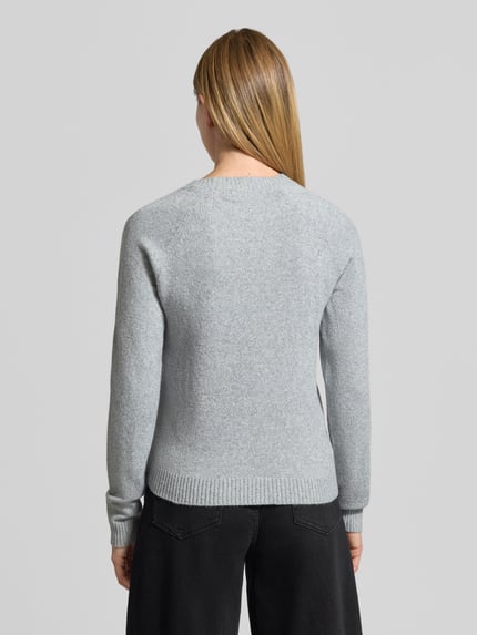 Frauenmodel trägt Pullover mit stricktypischer Strukturtextur von VERO MODA, grau, unifarben, Regular Fit, gerippte Abschlüsse, Ganzkörperansicht Rückansicht.