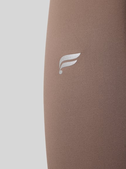 Produktfoto, braune Slim Fit Leggins mit Logo-Detail, Modell 'PURELUXE' von Fabletics, glatte Textur, Damen Leggins, Nahaufnahme.