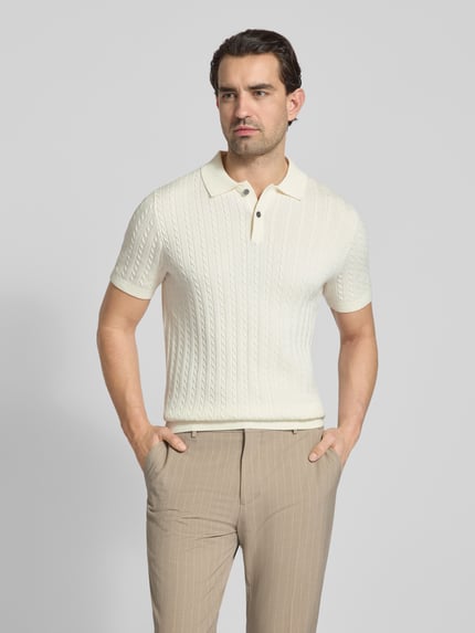 Męski model nosi Slim Fit Poloshirt in Strick-Optik von Christian Berg Men z bawełny, imitacja dzianiny, kołnierzyk polo, krótkie rękawy, kremowy, przód, ujęcie całej sylwetki.