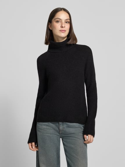 Modelka nosi Regular Fit Pullover aus Alpaka-Woll-Mix Modell 'Falodina' od BOSS Orange, czarny, dzianinowy, z golfem, długie rękawy raglanowe, unifarbny, optyka dzianiny, widok całej sylwetki z przodu.