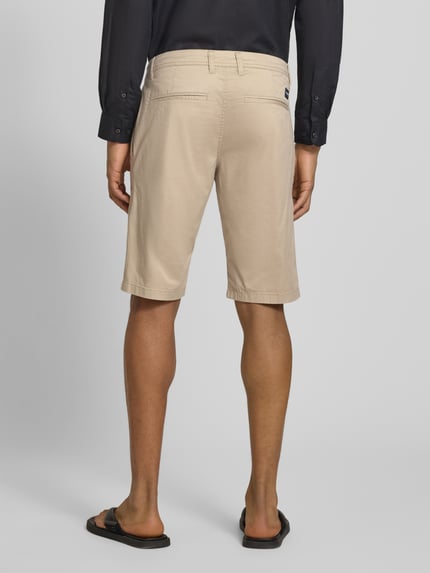 Männermodel trägt Slim Fit Chinoshorts aus Baumwoll-Mix von Tom Tailor, beiges feines Webmuster, Twill, Gesäßtaschen, Ganzkörperansicht Rückansicht.
