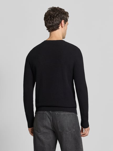 Männermodel trägt Pullover mit Strukturstrickoptik aus reiner Baumwolle von S.OLIVER CASUAL in Schwarz, Melange-Strick, Ganzkörperansicht Rückansicht.