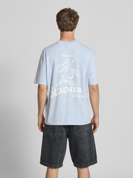 Männermodel trägt Oversized T-Shirt mit Label-Print von Pegador in Hellblau aus Reine Baumwolle, Rundhalsausschnitt, Rückenlänge 72 cm, Ganzkörperansicht Rückansicht.