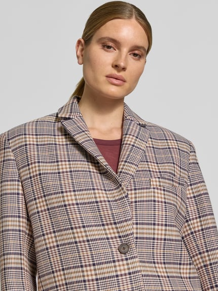 Frauenmodel trägt Regular Fit Longblazer aus Viskose-Mix von Anine Bing im Karo-Muster, Reverskragen, 2-Knopfverschluss, Nahaufnahme Oberkörper. Rückenlänge 75 cm, Brustweite 43 cm, Ärmellänge 61 cm.