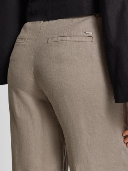 Frauenmodel trägt Leinenhose in verkürzter Passform von Christian Berg Woman in Beige, reine Leinenstruktur, Detailaufnahme Rückansicht.
